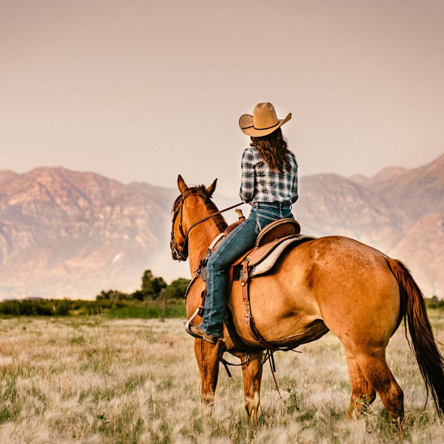 a woman on horseback takes in the sunset in Midway, Utah