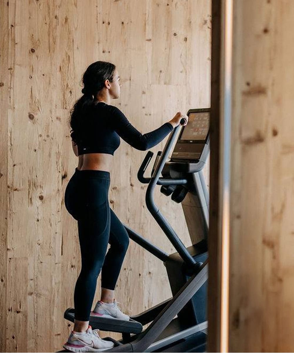 a woman exercises in the fully-equipped gym in the Homestead Residences Fitness and Activity Center