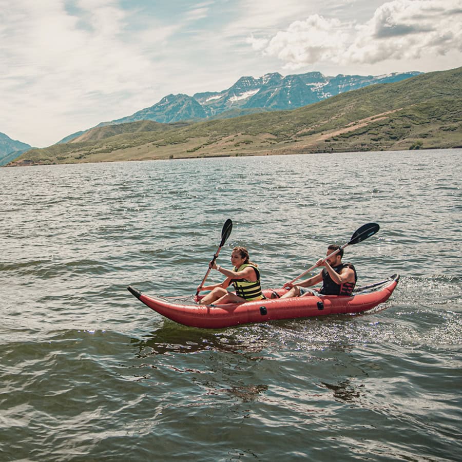 stunning mountain ranges surround two kayakers on the placid waters around Midway, Utah